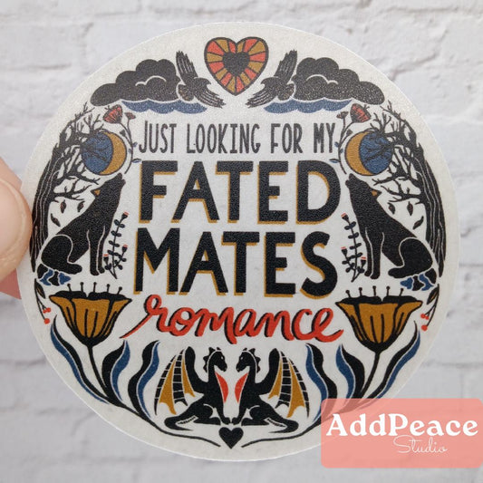 Circular sticker with decorative border and text 'Just looking for my fated mates romance' held against a light background.