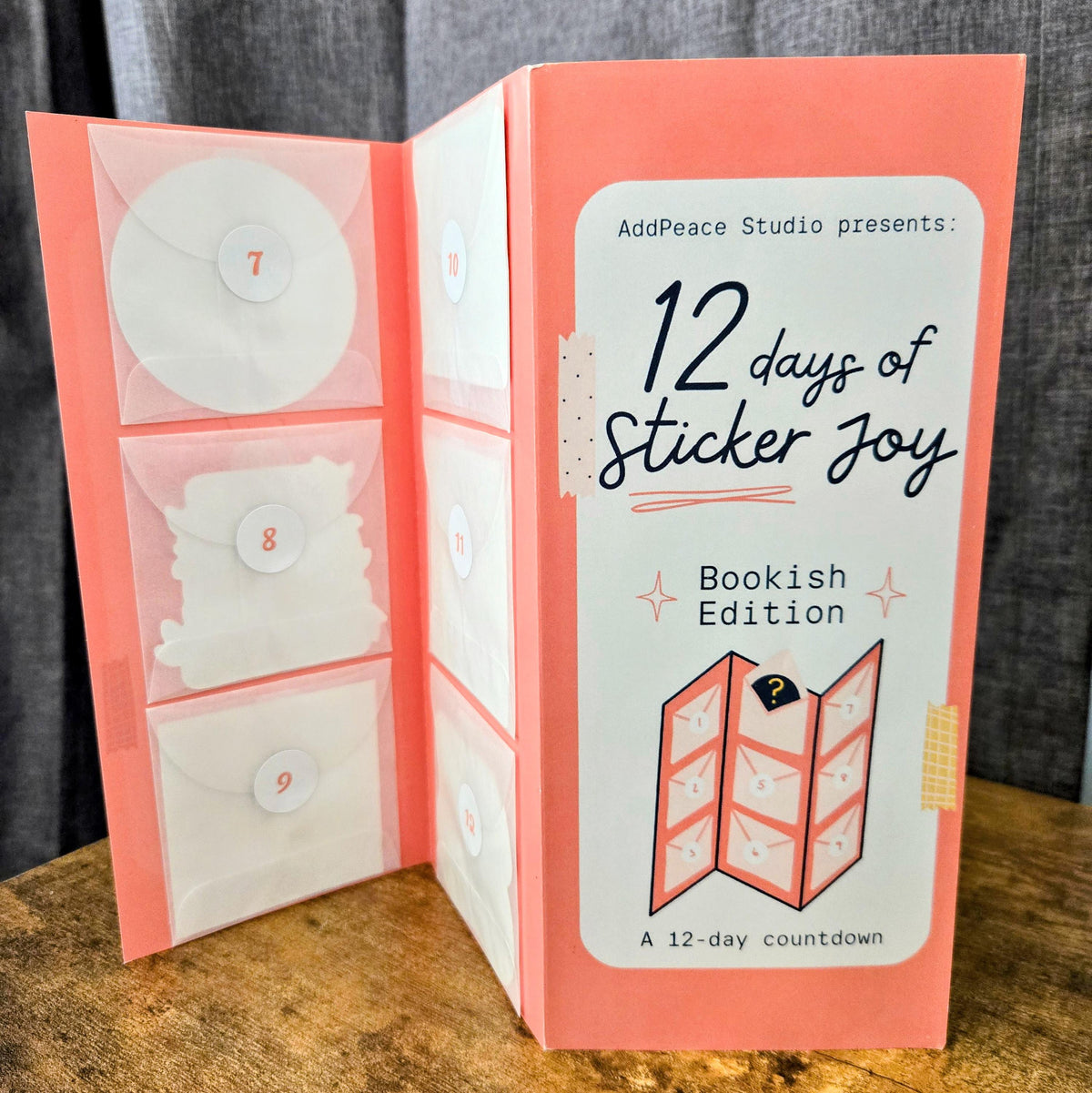 12 days of Sticker Joy Bookish Edition packaging on a wooden surface with a gray background