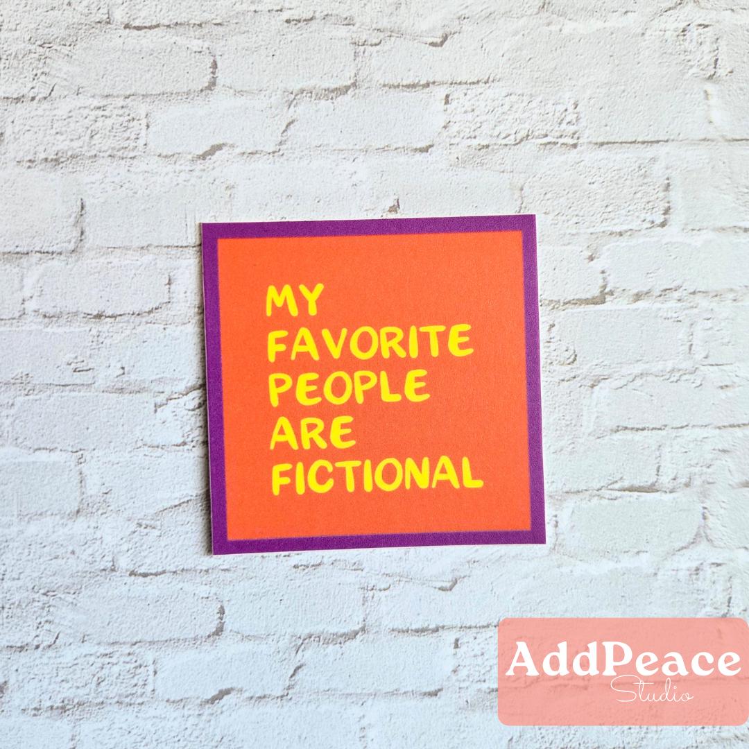 Orange sticker with yellow text 'My favorite people are fictional' on a white brick wall, featuring the brand 'AddPeace'.