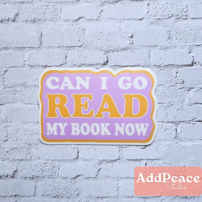 Sticker with 'Can I go read my book now?' text on a light blue brick wall background, featuring the brand 'AddPeace'.