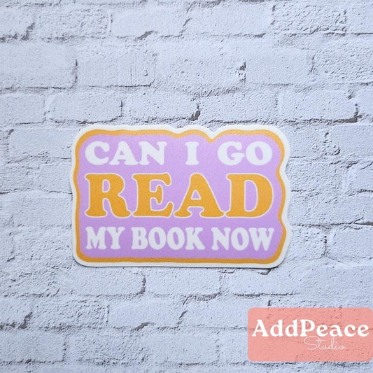 Sticker with 'Can I go read my book now?' text on a light blue brick wall background, featuring the brand 'AddPeace'.