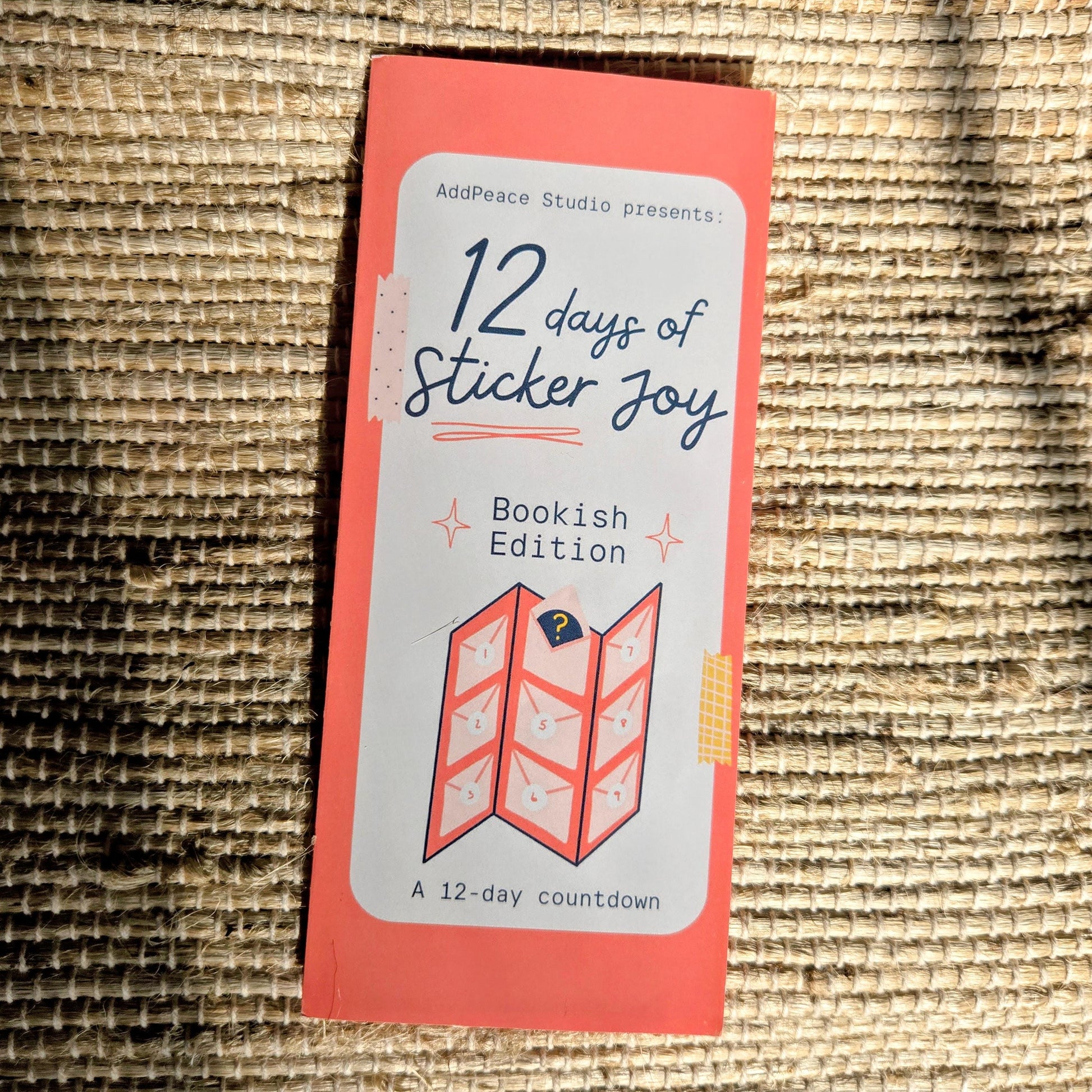 Packaging for '12 days of Sticker Joy' Bookish Edition on a textured surface