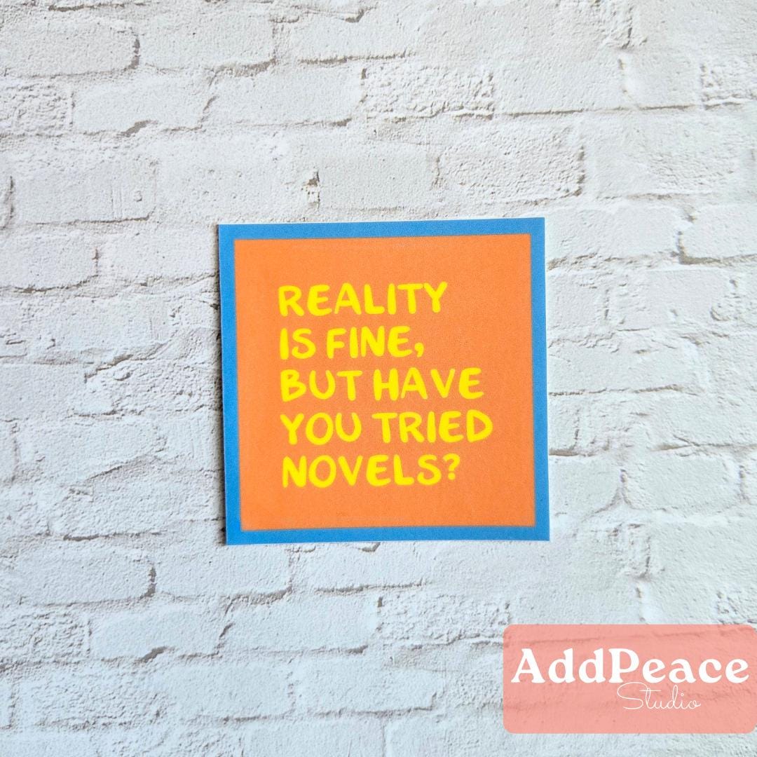 Orange sticker with Reality is fine but have you tried novels? on a brick wall with 'AddPeace Studios' branding.