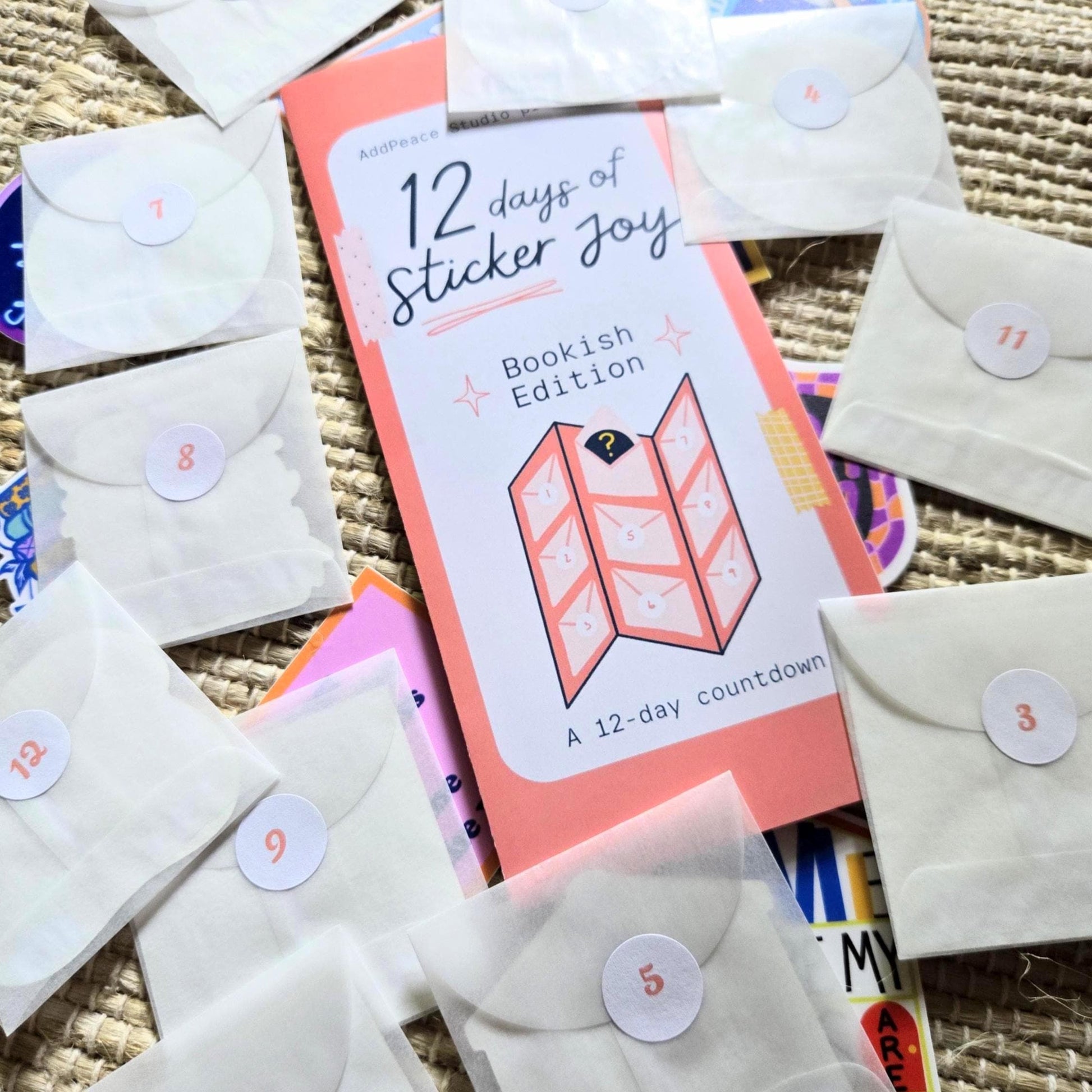 12 days of Sticker Joy Bookish Edition packaging with small envelopes on a textured surface