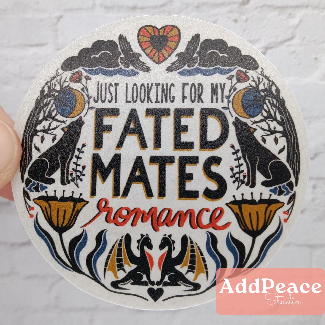 Circular sticker with decorative border and text 'Just looking for my fated mates romance' held against a light background.
