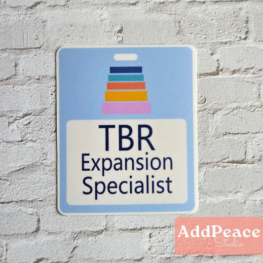 Sticker badge with 'TBR Expansion Specialist' text on a blue background, against a brick wall.