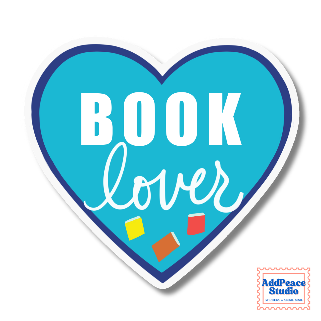 A heart-shaped sticker with a bright blue background and dark blue border, featuring the words 'BOOK lover' in white. Small colorful book icons are printed near the bottom.
