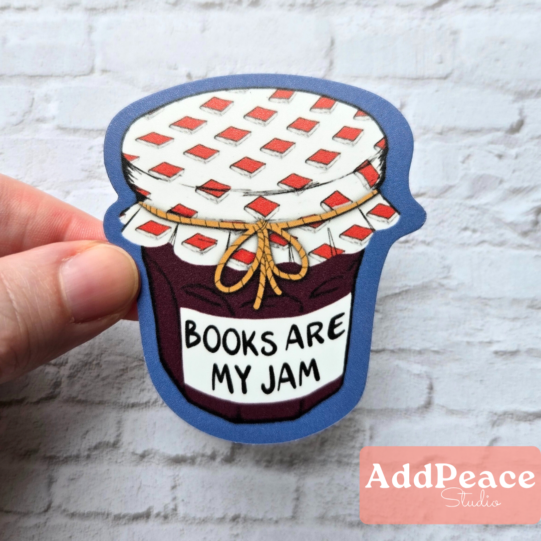 Sticker of a jam jar with 'Books are my jam' text, held by a hand against a textured white background.
