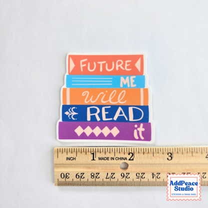 A small rectangular sticker with stacked colorful book shapes and the phrase “FUTURE ME will READ it,” shown above a wooden ruler for scale on a light gray background. A small AddPeace Studio watermark appears in the bottom right corner.