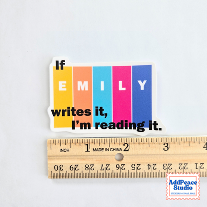 A die-cut sticker with the text 'If EMILY writes it, I'm reading it.' placed above a wooden ruler to show scale.