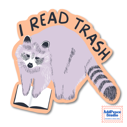 A die-cut sticker featuring a stylized raccoon reading an open book, with the text “I READ TRASH” arched above it. The sticker has a peach outline and is shown on a plain white background.