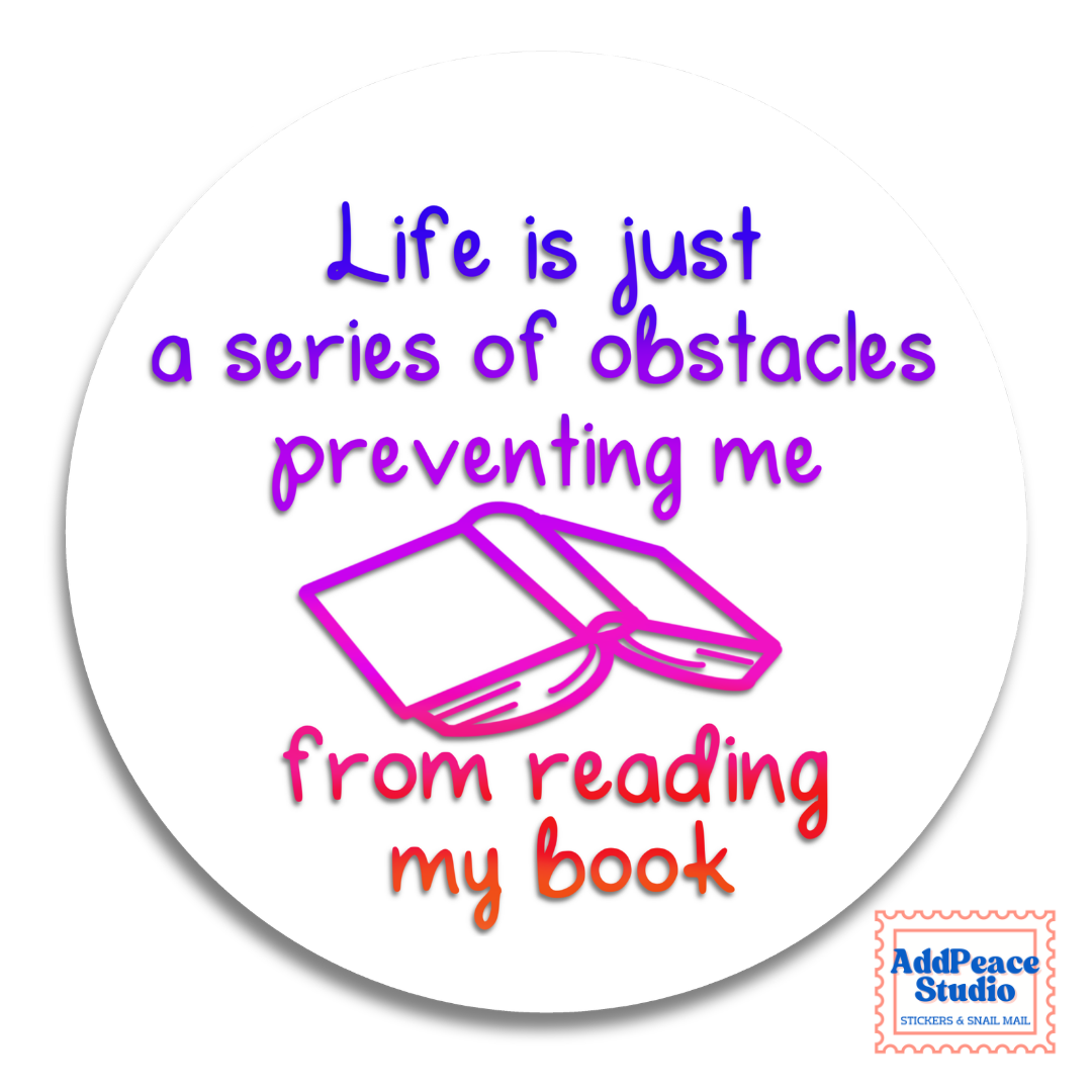A round white sticker with a printed quote that reads 'Life is just a series of obstacles preventing me from reading my book' in purple and orange lettering, alongside a pink outline illustration of an open book. The AddPeace Studio logo is in the bottom right corner.