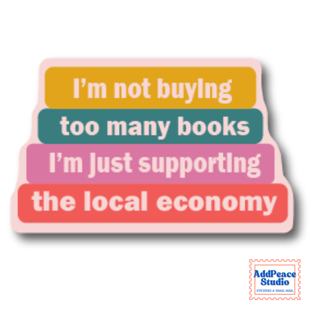 A die-cut sticker with a retro layered design featuring four stacked pastel-colored books with white text that reads, 'I'm not buying too many books I'm just supporting the local economy.' The sticker is shown on a clean white background with a small 'AddPeace Studio' brand logo in the bottom right corner.