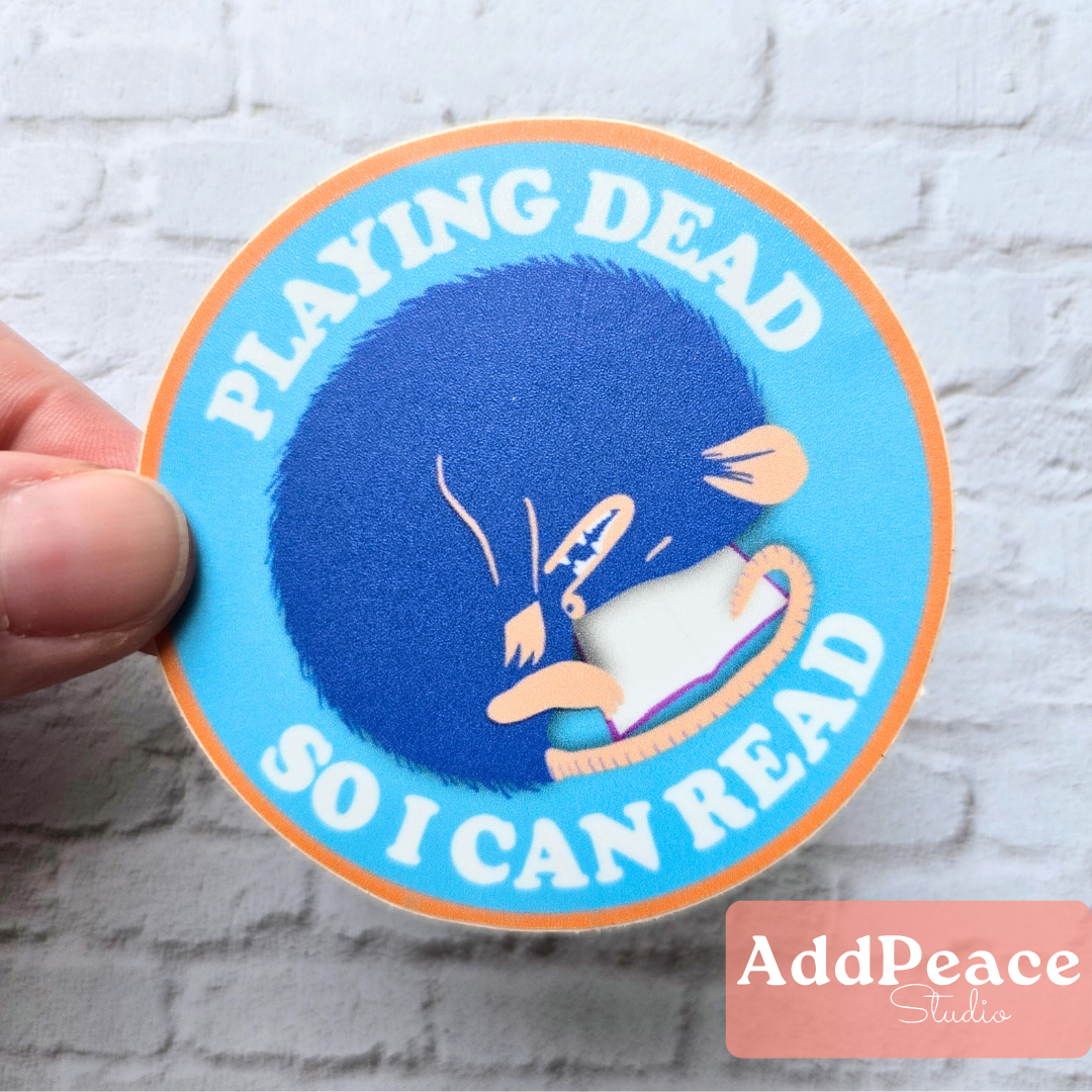 Curled up possum reading a book vinyl sticker with “Playing Dead So I Can Read” text