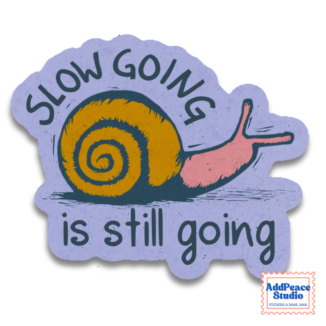 A die-cut sticker featuring a stylized snail with a mustard-yellow shell and pink body on a lavender background, with the text 'SLOW GOING is still going' in dark teal lettering. An AddPeace Studio logo is visible in the bottom right corner.