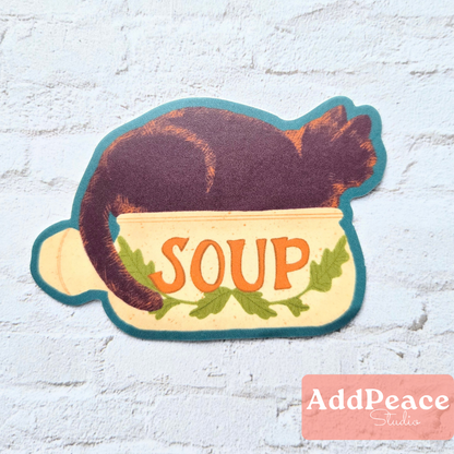 Sticker of a cat in a bowl labeled 'SOUP' with 'AddPeace Studios' logo.