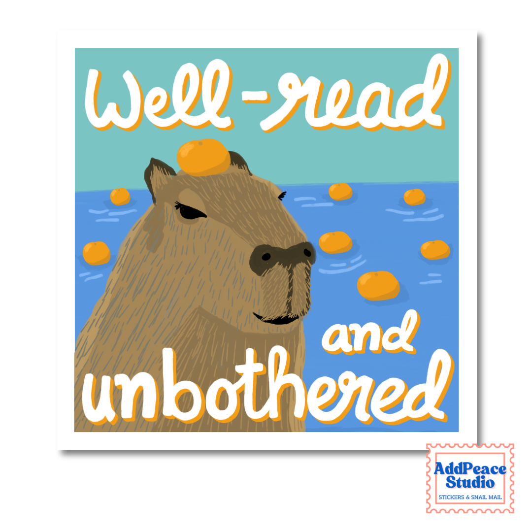 A square sticker or art print featuring an illustrated capybara in blue water with the text 'Well-read and unbothered' in white with orange outlines. A small 'AddPeace Studio' logo appears in the bottom-right corner.