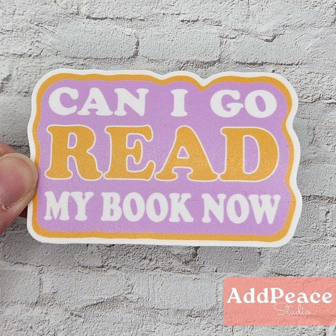 Sticker with text 'CAN I GO READ MY BOOK NOW' held against a textured gray background, with 'AddPeace Studios' logo.